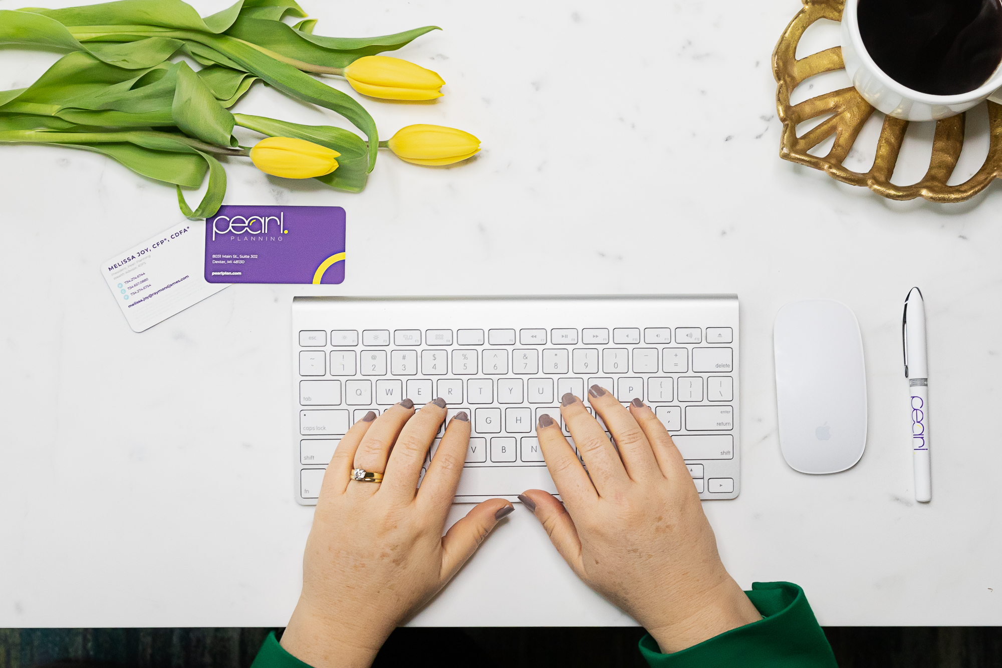 two hands typing ion a keyboard with cup of coffee and Pearl Planning business card