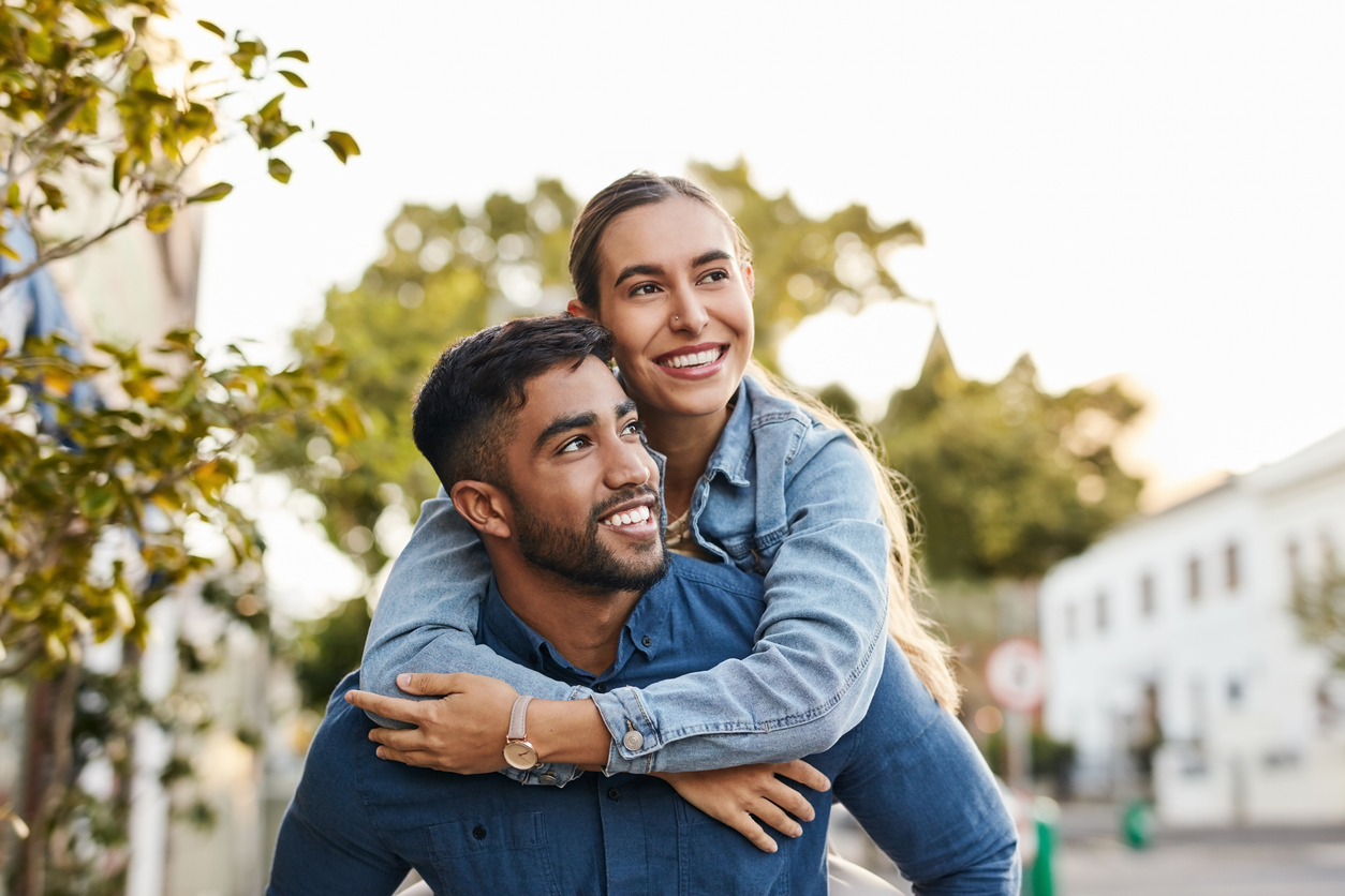 Travel, piggyback and happy couple with love in the city on a walk while on a romantic date. Happiness, smile and young man and woman having fun, walking and bonding in the town street on a vacation.